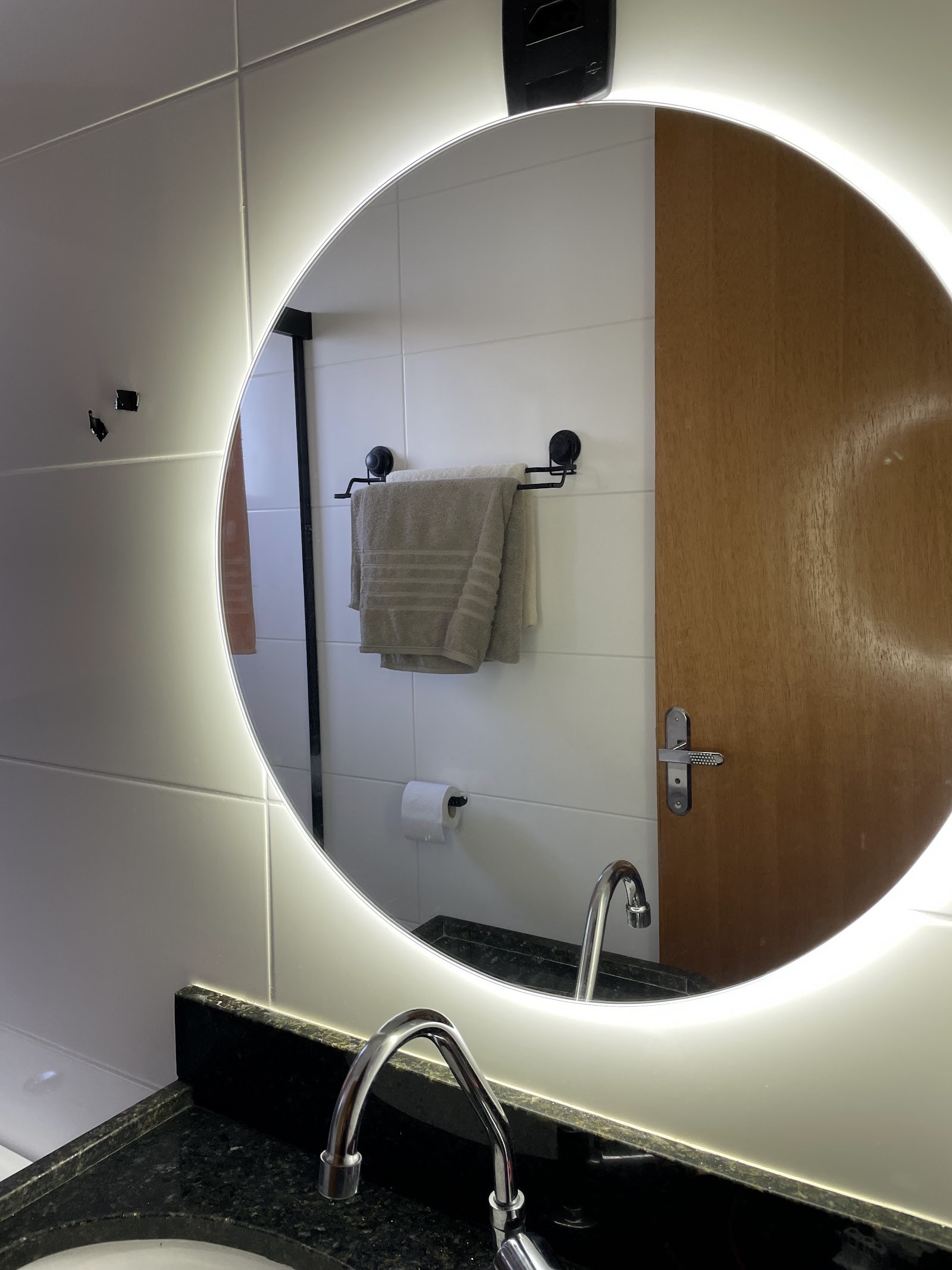 Espelho redondo com iluminação de LED instalado em banheiro